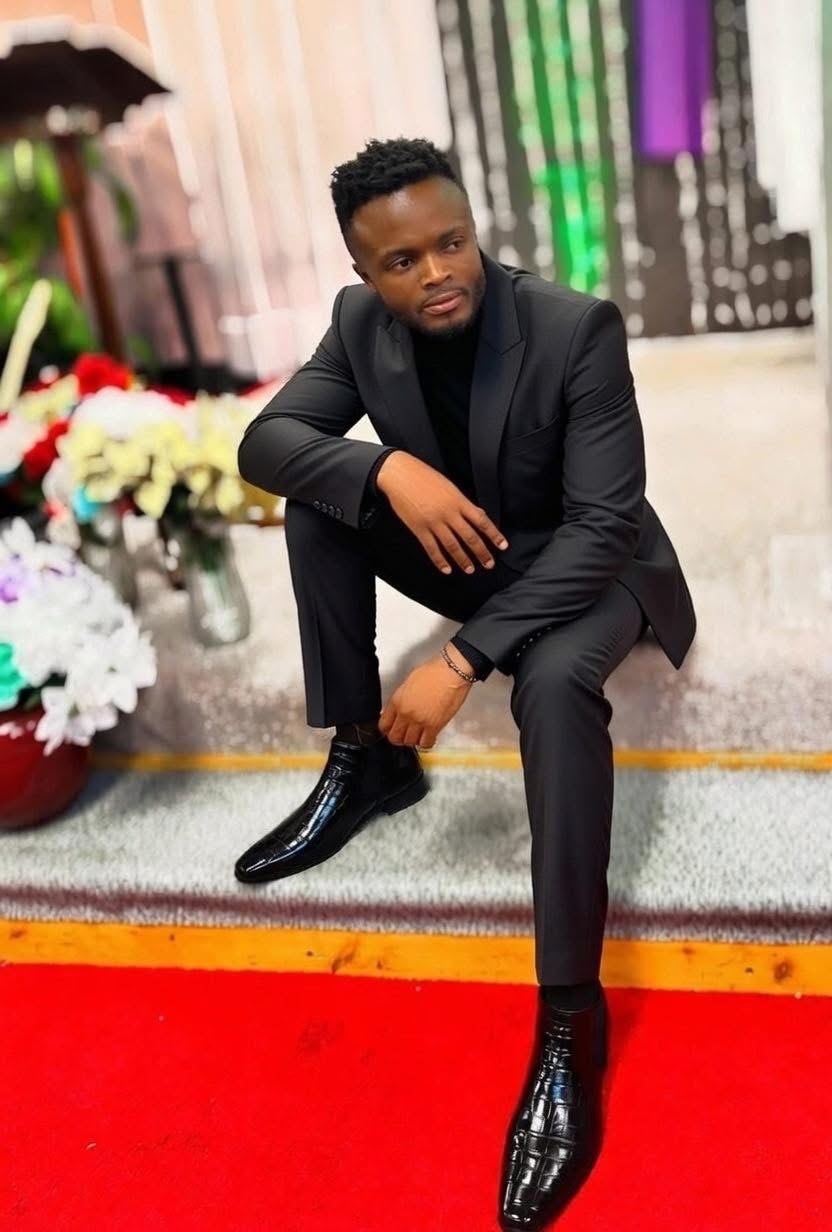 DE LA ROSE in a black suit indoors